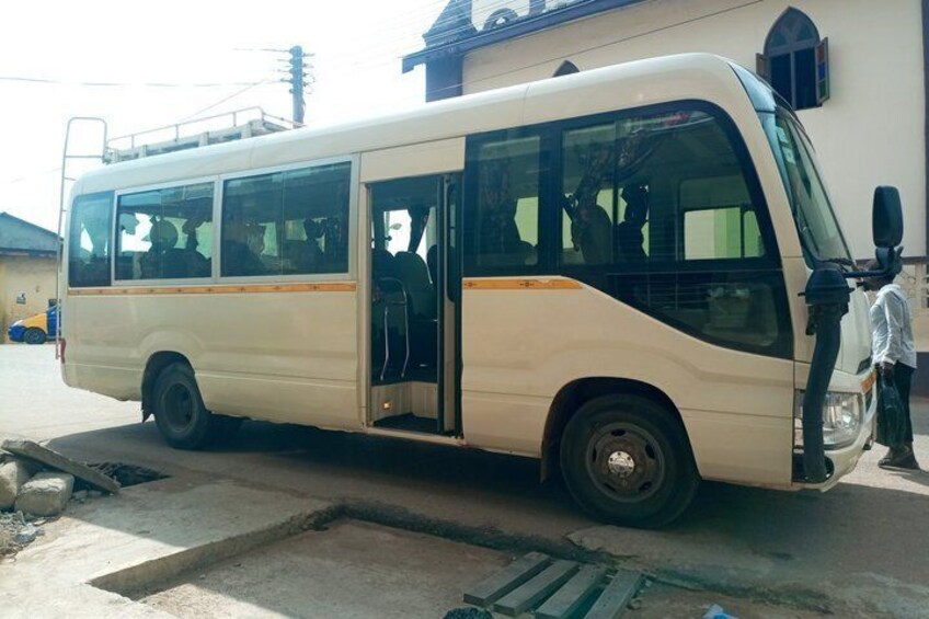 A white bus parked on a street with a person standing beside it. 4