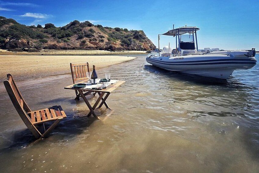 A boat on a beach with a table and chairs set up in shallow water. 1