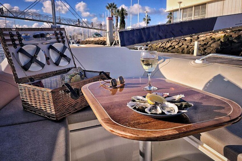 A table with a plate of oysters and a glass of white wine on a boat deck. 3