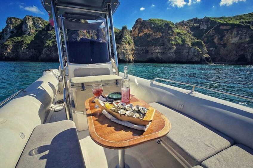 A boat with a wooden tray table holding food and drinks, surrounded by clear blue water and rocky cliffs. 4