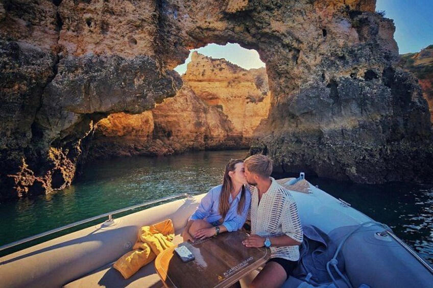 A boat with two people sitting at the front, a rocky coastline, and a natural arch formation. 2