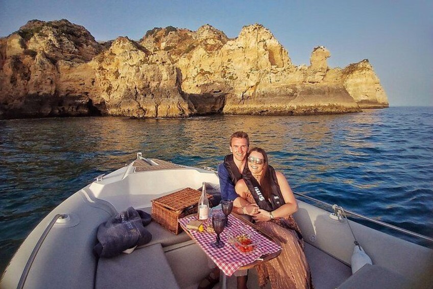 A boat with two people, a rocky coastline, and clear blue water. 5
