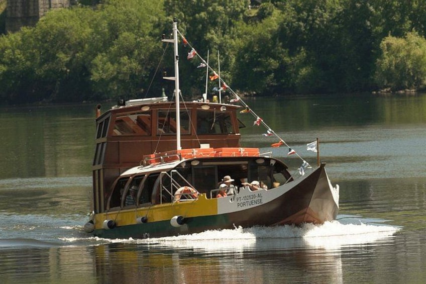 A ferry boat with passengers, moving on calm water with trees in the background. 1