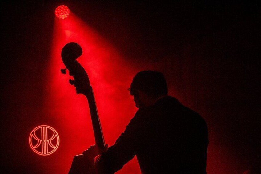 A silhouette of a person playing a guitar under red stage lighting. 3