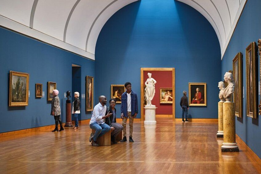 An art gallery with wooden floors, blue walls, and various paintings and sculptures. 2