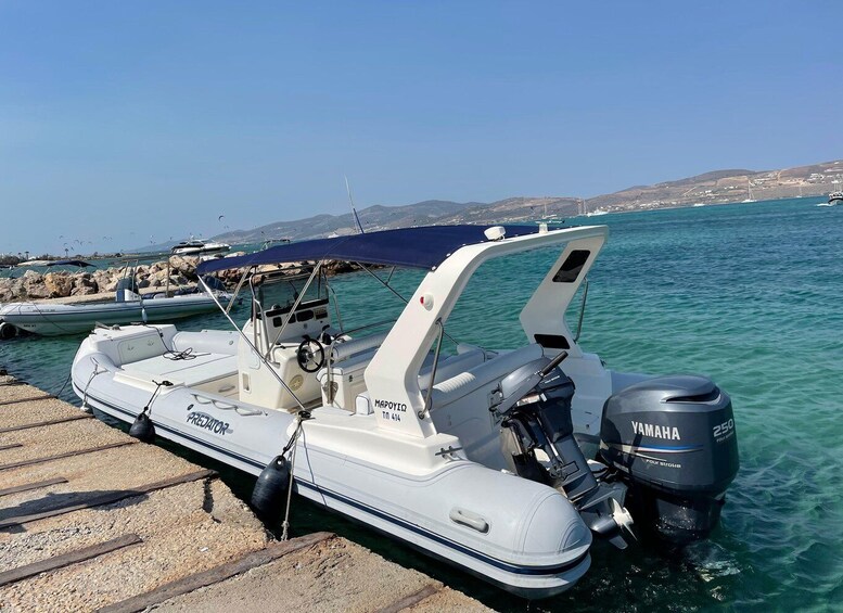 A white motorboat with a Yamaha engine docked at a pier with clear turquoise water and a hilly landscape in the background. 5