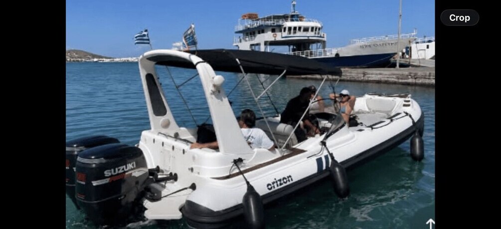 A white motorboat with 'Suzuki' and 'Citizen' branding, docked at a marina with calm water and a clear sky. 2