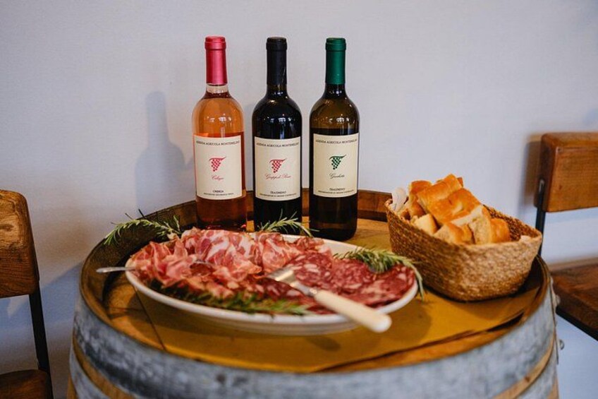 A wooden barrel, a plate of cured meats, a basket of bread, and three wine bottles. 2