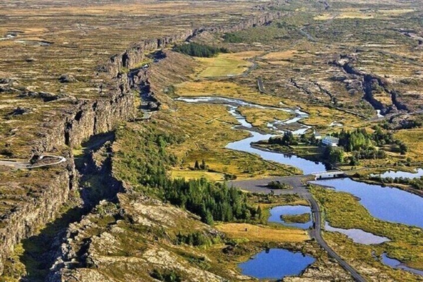A rugged landscape with a river, rocky cliffs, and scattered ponds. 1