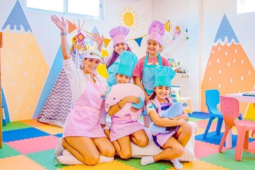 Children in a playroom with colorful mats, a table, chairs, and a tent-like structure. 4