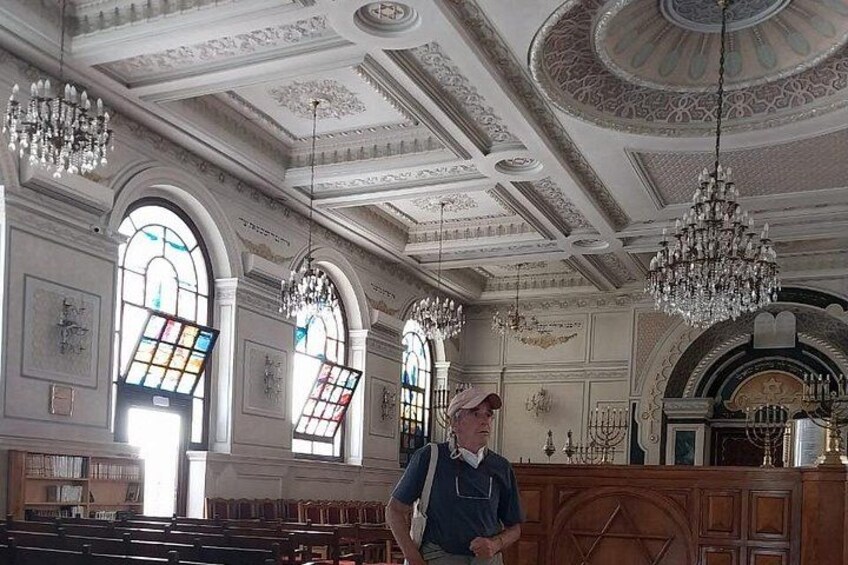 A grand hall with ornate chandeliers, stained glass windows, and a wooden pew arrangement. 4