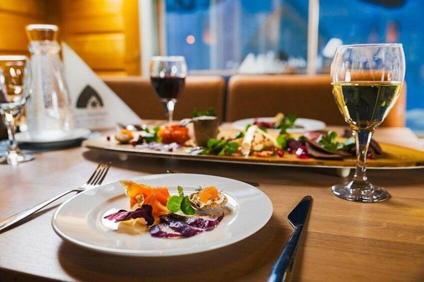 A dining table with plates of food, a wine glass, and cutlery. 2