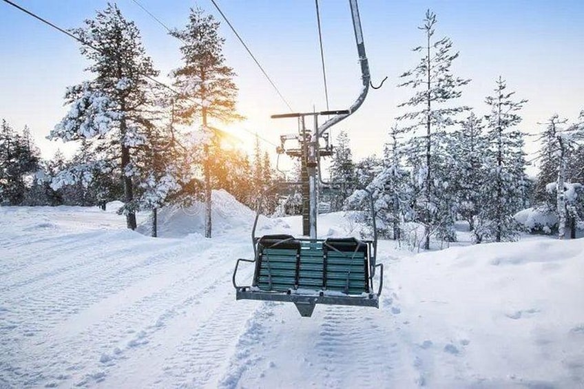 A ski lift chair suspended over a snowy landscape with trees and a clear sky. 5