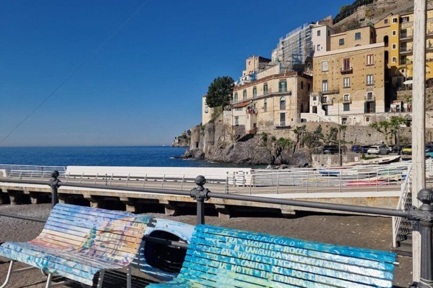 Una zona costera con edificios coloridos, un muelle y un banco con un mapa. 5