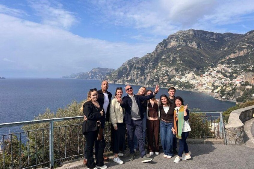 Un grupo de personas en un sendero costero, con vista al mar y montañas al fondo. 2