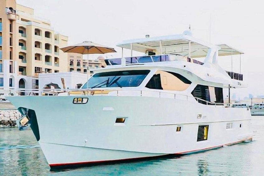 Un yate blanco grande amarrado en un puerto deportivo, con edificios al fondo. 1