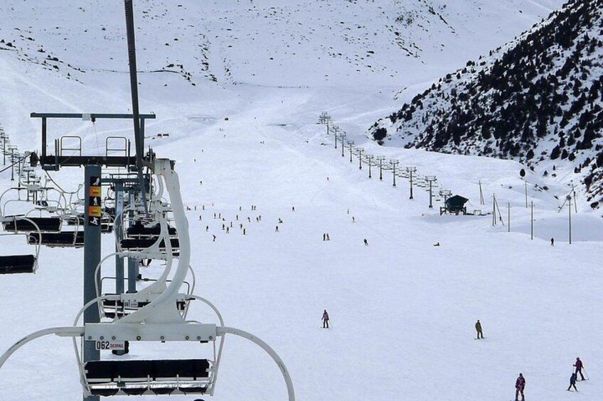 A ski lift chair, a snowy mountain slope, and skiers. 2