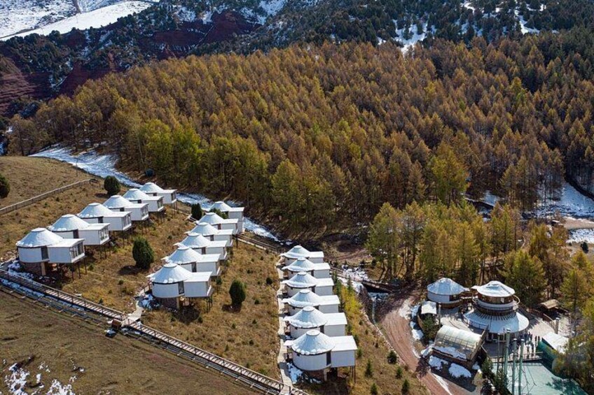 A mountainous area with yurts and a traditional building. 5