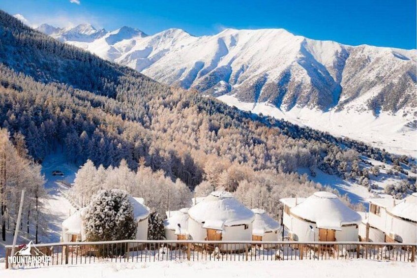 A snow-covered mountain landscape with a cluster of white buildings in the foreground. 1