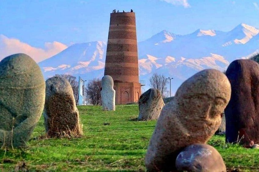 A stone tower, several standing stones, and a mountain range in the background. 1