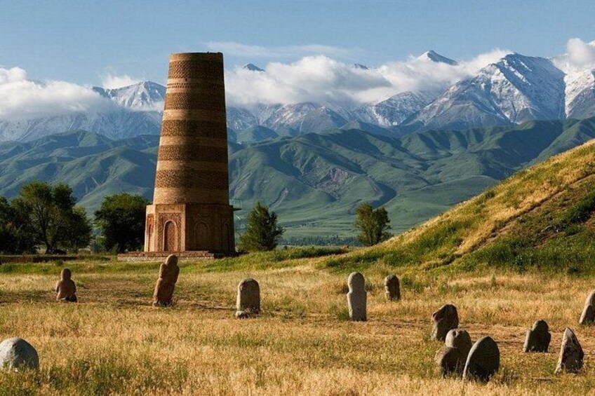 A stone tower, gravestones, and a mountainous landscape. 5