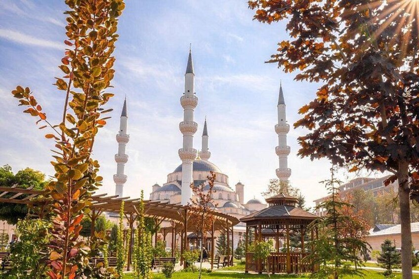 A mosque with four minarets, a dome, and a garden with trees and a gazebo. 2