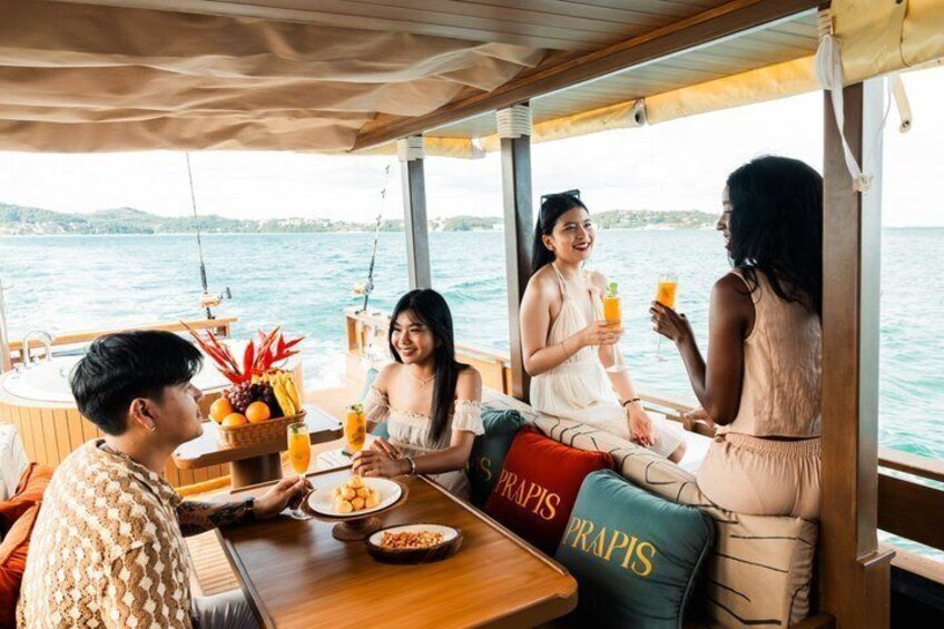 Un groupe de personnes est réuni autour d’un repas sur un bateau, avec vue sur l’eau. 5