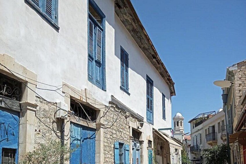 A narrow street with white buildings, blue shutters, and a dome in the distance. 3