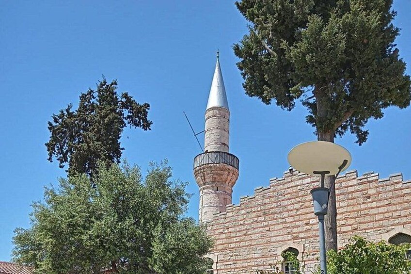A brick building with a tall tower and a pointed spire. 2