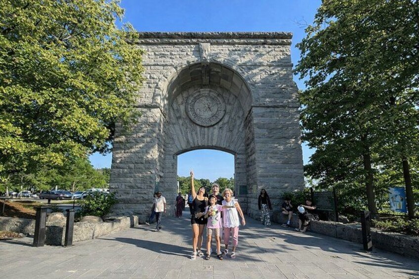 A stone archway with people standing in front of it. 3
