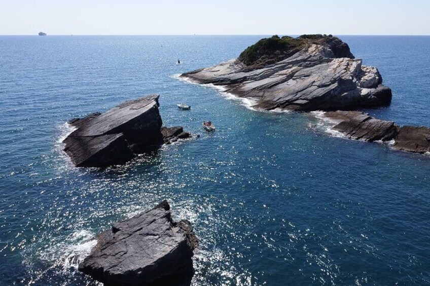 A rocky coastline with large boulders and clear blue water. 1