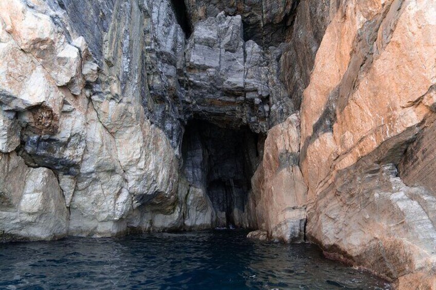 A rocky cave entrance with water at the base. 4