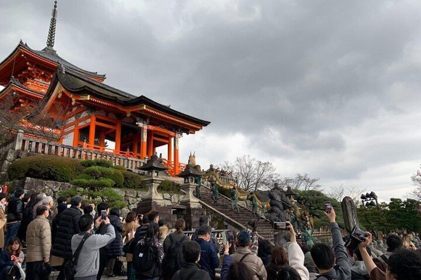 A traditional Japanese temple with a red roof, surrounded by a crowd of people. 3