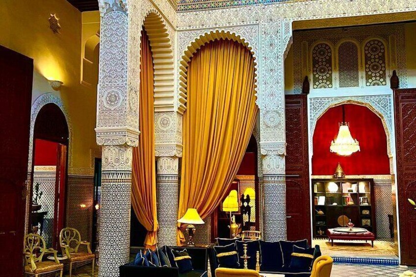 An ornate interior with intricate tile work, a large golden curtain, and traditional furniture. 4
