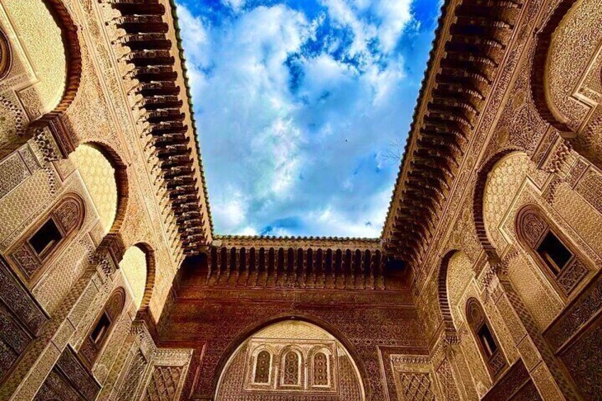 An ornate courtyard with intricate arches and a view of the sky. 5