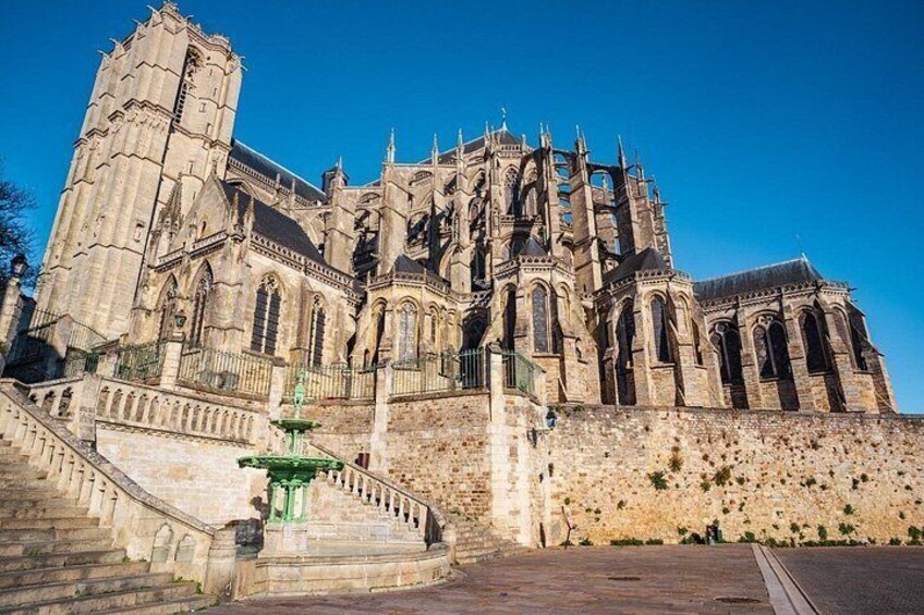 A large Gothic cathedral with intricate architecture, a prominent tower, and a green fountain in the foreground. 3