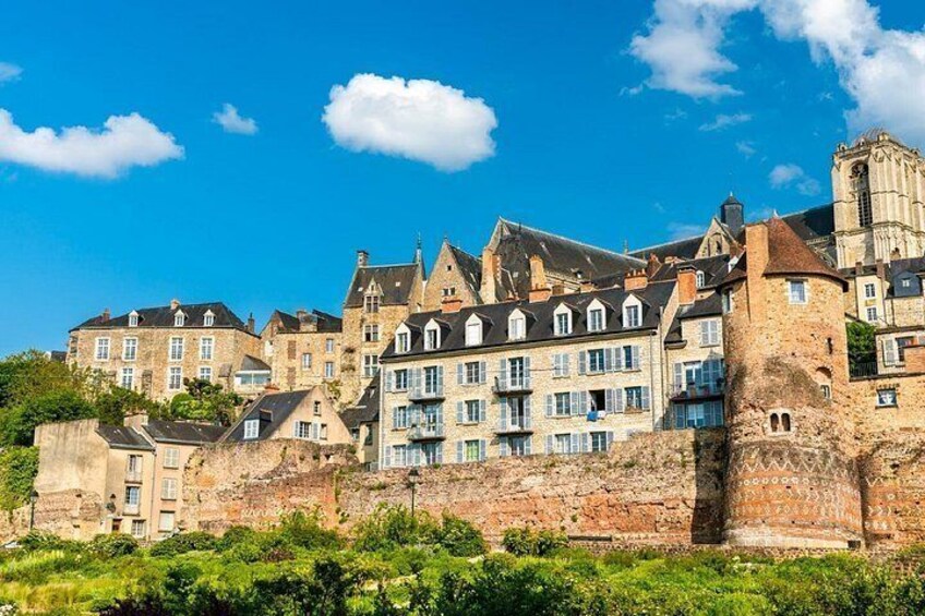 A historic town with stone buildings, a prominent church tower, and a fortified wall. 2