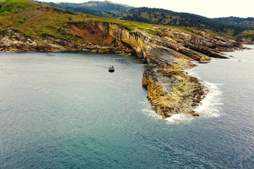 A coastal landscape with cliffs, a body of water, and a small boat. 2