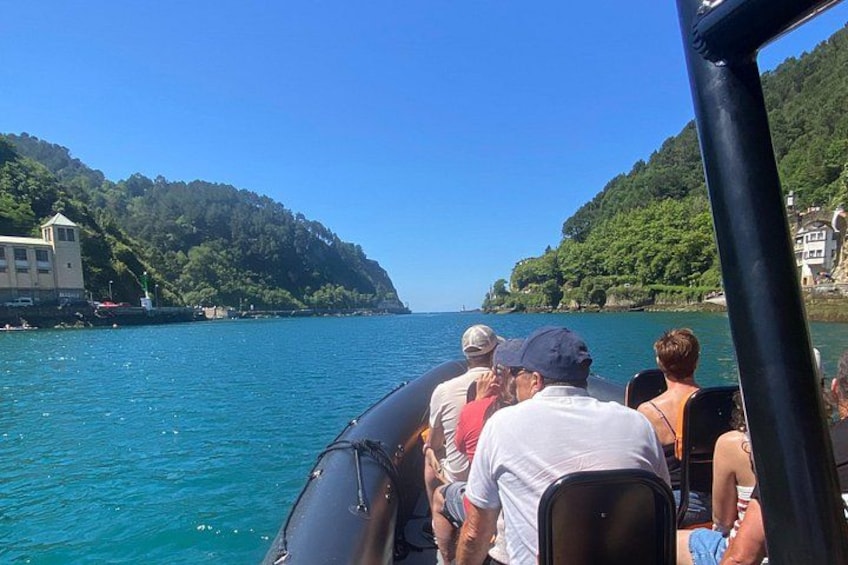 Un bote con gente en un día despejado, rodeado de aguas tranquilas y colinas verdes. 1