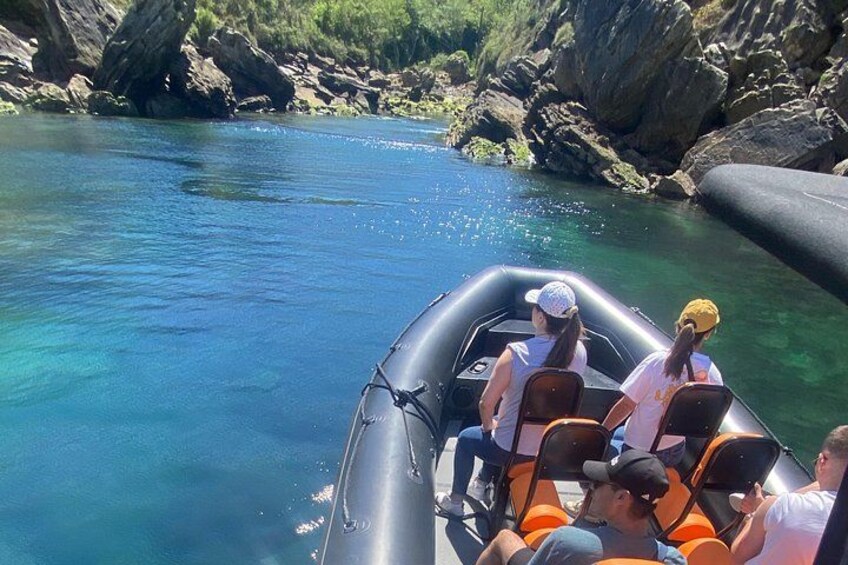 A group of people on a raft in clear blue water surrounded by rocky terrain. 2