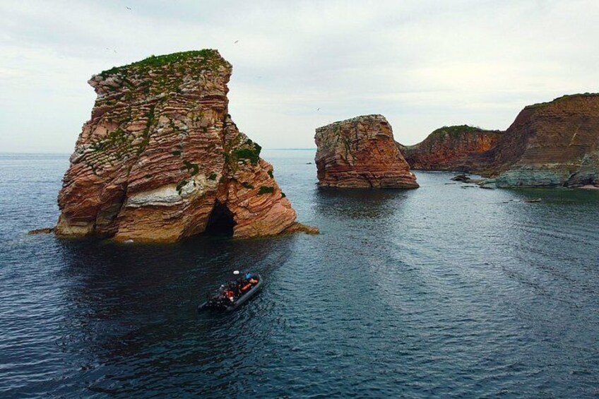 A boat navigating between two large rock formations in a body of water. 5