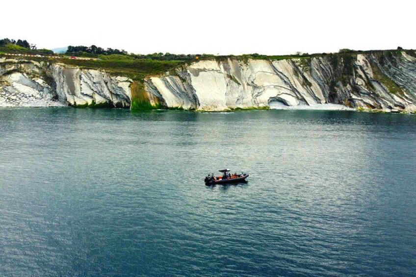 A boat on calm water with cliffs in the background. 2