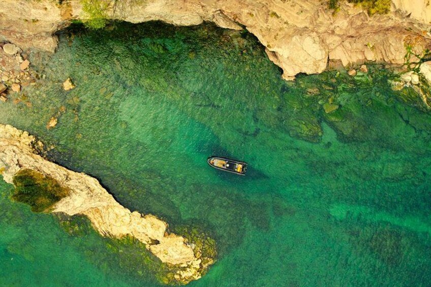 A boat in clear turquoise water near rocky cliffs. 4