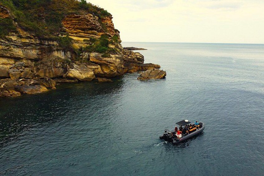 A boat on calm water near a rocky coastline. 3