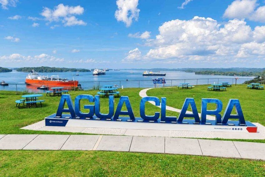 A sign reading 'AGUACLARA' with picnic tables and a view of a lake with boats. 4