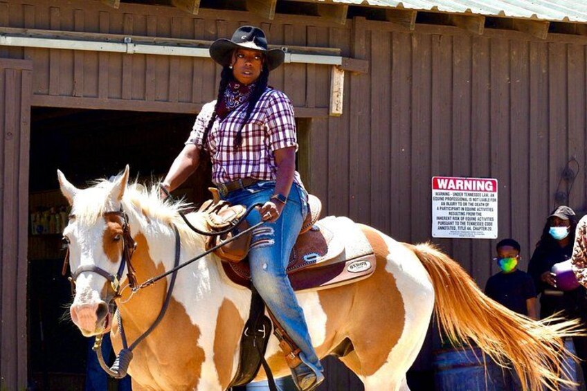 A person riding a horse in front of a wooden building with a warning sign. 3