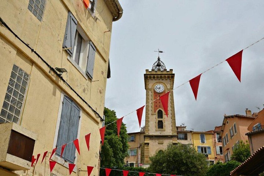 Un edificio storico con una torre dell'orologio, circondato da altri edifici e bandiere triangolari rosse. 3