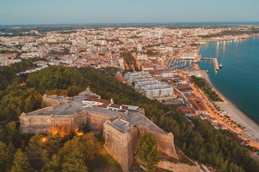 An aerial view of a coastal city with a prominent fort, dense urban area, and a large body of water. 2