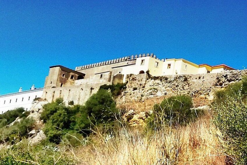 A historic stone fortress on a hill with a clear sky. 3