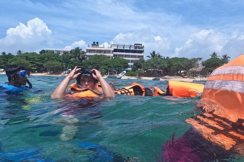 People in water with life jackets and a building in the background. 5